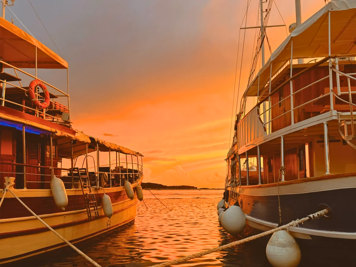 Wooden boats moored under a glowing orange sunset